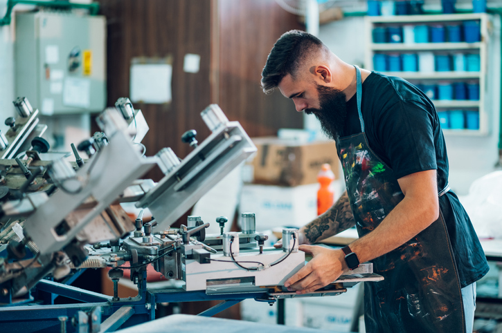 Male worker using a printing machine in a workshop